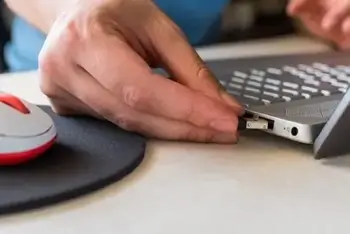 An image of a person plugging a USB dongle into a computer